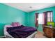 Vibrant bedroom with bright turquoise walls and a plush purple blanket, showcasing a cozy retreat at 6205 W Encinas Ln, Phoenix, AZ 85043