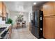 Kitchen with black refrigerator, wood cabinetry, and tile flooring next to the dining area at 6205 W Encinas Ln, Phoenix, AZ 85043