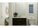 A lovely powder room with a dark vanity, white countertop, round mirror, and stylish accents at 7848 W Tether Trl, Peoria, AZ 85383