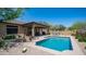 Sparkling pool with covered patio, hot tub, and desert landscaping offer a serene backyard retreat at 9037 E Indigo St, Mesa, AZ 85207