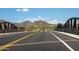 Street view with a bridge and scenic mountain backdrop, highlighting the community's access and beautiful setting at 9037 E Indigo St, Mesa, AZ 85207