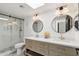 Modern bathroom with a walk-in shower, skylight, double vanity, and round mirrors at 12835 N 78Th St, Scottsdale, AZ 85260
