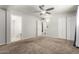 A carpeted primary bedroom with a ceiling fan and access to the en-suite bathroom and a walk-in closet at 1545 W 7Th Ave, Mesa, AZ 85202