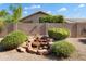 Backyard showcasing a rock waterfall feature, lush shrubs, desert landscaping, and mature foliage at 17653 W Ingleside Dr, Surprise, AZ 85374