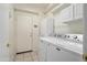 Functional laundry room with machines, storage cabinets, and tile floors, offering convenience and ample space at 17653 W Ingleside Dr, Surprise, AZ 85374