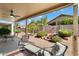 Covered patio featuring an outdoor seating area, ceiling fan, and picturesque landscaping with a rock waterfall at 17653 W Ingleside Dr, Surprise, AZ 85374