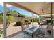 Inviting covered patio with seating area and a view of the landscaped yard with a rock waterfall feature at 17653 W Ingleside Dr, Surprise, AZ 85374