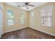 Bright bedroom with warm walls, wood floors, arched windows, and ceiling fan at 21017 W Edith Way, Buckeye, AZ 85396