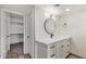 Bathroom with white cabinets, modern fixtures, a sleek round mirror, and a door to closet at 2107 W Lane Ave, Phoenix, AZ 85021