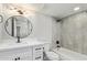 Bright bathroom featuring a round mirror, single vanity, shower over tub, and tiled walls at 2107 W Lane Ave, Phoenix, AZ 85021