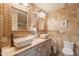 Bathroom boasts dual sinks, stone countertops, framed mirrors, and a toilet, offering a spa-like retreat at 21311 N Shelby Ct, Maricopa, AZ 85138