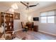 Cozy bedroom featuring a ceiling fan, hardwood floors, built in bookcase and desk, and a mounted TV at 21311 N Shelby Ct, Maricopa, AZ 85138