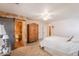 A bedroom featuring a wardrobe, a stone accent wall, and an ensuite bathroom with a sliding barn door at 21311 N Shelby Ct, Maricopa, AZ 85138