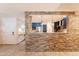 Open kitchen with stainless steel appliances, dark cabinetry, and a stone accent wall, connecting to the entryway at 21311 N Shelby Ct, Maricopa, AZ 85138