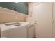 The laundry room features a modern washer and dryer, cabinets, and a convenient access door at 21311 N Shelby Ct, Maricopa, AZ 85138