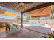 Under a decorative ceiling, the patio offers cushioned seating, shade sails, and views of a swimming pool at 21311 N Shelby Ct, Maricopa, AZ 85138