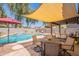 Resort-style backyard featuring a beautiful pool, shade structure, and outdoor dining area, perfect for entertaining at 21311 N Shelby Ct, Maricopa, AZ 85138