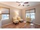 Bright sitting area with wood floors, two chairs, a ceiling fan and two windows for ample natural light at 21311 N Shelby Ct, Maricopa, AZ 85138