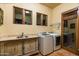 Well-equipped laundry room with modern washer and dryer, built-in sink, and ample cabinet space at 40039 N 107Th Pl, Scottsdale, AZ 85262