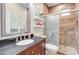 Stylish bathroom featuring a granite countertop, decorative shelving, and a tiled shower with glass door at 708 E Dry Creek Rd, San Tan Valley, AZ 85143