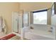 Bright bathroom features a soaking tub, glass enclosed shower, and a large sunny window at 708 E Dry Creek Rd, San Tan Valley, AZ 85143