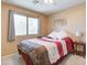 Cozy bedroom with a ceiling fan, window, and comfortable bed with red and brown patterned bedding at 708 E Dry Creek Rd, San Tan Valley, AZ 85143