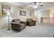 A carpeted living room with leather chairs, a ceiling fan, and neutral walls with a stairway nearby at 708 E Dry Creek Rd, San Tan Valley, AZ 85143