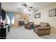 A carpeted living room featuring two leather chairs, a ceiling fan, and a window with nice light at 708 E Dry Creek Rd, San Tan Valley, AZ 85143