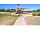 Community playground with covered picnic tables and play equipment surrounded by grass and landscaping at 708 E Dry Creek Rd, San Tan Valley, AZ 85143