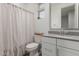 Bright bathroom with a white shower curtain, white vanity, and window with blinds at 9642 E Tesla Ave, Mesa, AZ 85212
