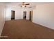Large carpeted main bedroom featuring neutral walls, ceiling fan and arched doorway to the bathroom at 1381 E Prickly Pear Dr, Casa Grande, AZ 85122