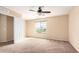 Bedroom showcasing neutral paint and carpet, ceiling fan, window, and white door at 18774 N Ibis Way, Maricopa, AZ 85138
