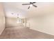 Large open area features neutral walls, carpet, a ceiling fan, and lots of natural light at 18774 N Ibis Way, Maricopa, AZ 85138