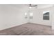Spacious bedroom with neutral carpet, ceiling fan, and bright windows at 14241 W Bronco Trl, Surprise, AZ 85387