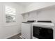 Functional laundry room with washer, dryer, window, and open shelving for storage at 14241 W Bronco Trl, Surprise, AZ 85387