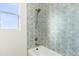 Bathroom shower/tub combo with patterned tile surround and window at 15582 W Jomax Rd, Surprise, AZ 85387