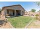 Backyard with green grass, covered patio, gravel perimeter, and block wall with fire pit at 17056 W Bristol Ln, Surprise, AZ 85374