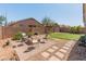 Paver and gravel backyard featuring a brick fire pit with chairs, grass, and block wall for privacy at 17056 W Bristol Ln, Surprise, AZ 85374