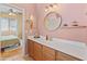 Bathroom with vanity, open access to bedroom and featuring a round mirror and sconce lighting at 17056 W Bristol Ln, Surprise, AZ 85374