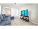 Bright, open living room with a comfortable gray sectional, tile floors, and a large TV at 24552 W Hilton Ave, Buckeye, AZ 85326