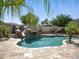 Lush backyard pool area with a rock slide, palm trees, and plenty of space for entertaining and enjoying the Arizona weather at 2822 E Constance Way, Phoenix, AZ 85042