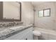 Bright bathroom features tub and shower combination, white marble tiling, modern vanity with light gray granite countertop and stainless steel fixtures at 3209 N 20Th Pl, Phoenix, AZ 85016