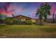 Charming single-story home featuring manicured lawn and mature shade tree under a colorful sky at 3936 E Oak St, Phoenix, AZ 85006
