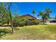 Quaint single-story home features a lush lawn and mature trees under a clear blue sky at 3936 E Oak St, Phoenix, AZ 85006