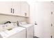 Bright laundry room with modern, front-loading washer and dryer and ample storage in white cabinets at 8226 W Swansea Dr, Arizona City, AZ 85123