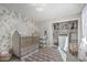 Charming Bedroom features a crib, floral wallpaper, closet with storage, and neutral colored area rug at 401 E Barbara Dr, Tempe, AZ 85288
