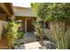 The home features a welcoming front entrance surrounded by vibrant greenery and decorative rock ground cover at 4525 N 66Th St # 112, Scottsdale, AZ 85251