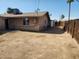 A sunny backyard displays the exterior of the home, dirt landscaping, and a wood fence at 6017 W Colter St, Glendale, AZ 85301
