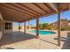 Covered patio overlooking a backyard with a swimming pool, mature trees, and desert landscaping at 7709 W Hearn Rd, Peoria, AZ 85381
