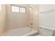 This bathroom features a tiled shower-tub combination with a window for natural light and ventilation at 7709 W Hearn Rd, Peoria, AZ 85381